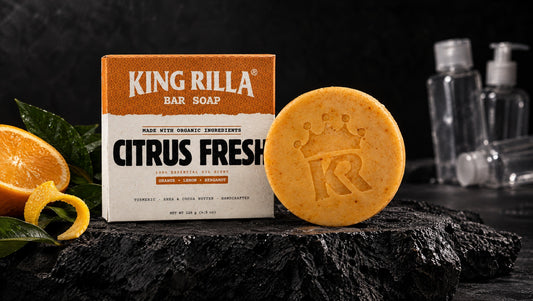 King Rilla Citrus Fresh soap and carton on dark stone beside empty plastic toiletry bottles.