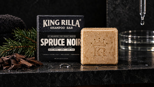 King Rilla Spruce Noir shampoo bar and carton on a dark shower shelf.