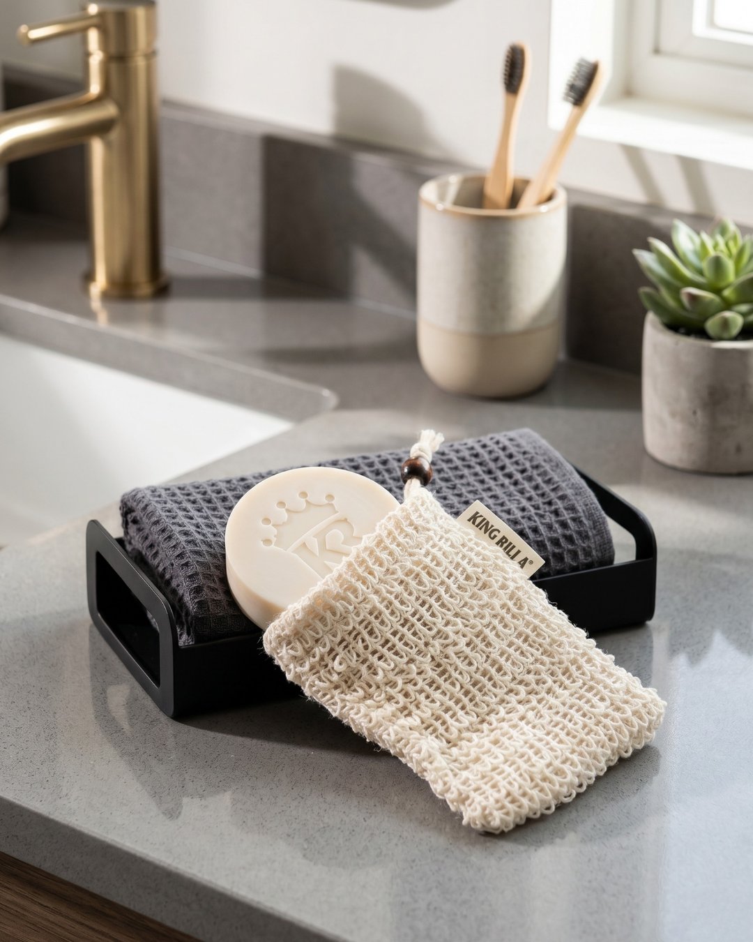 King RIlla soap dish with a bar of soap and a natural sponge on a kitchen counter.