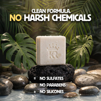 Bar of soap with a brand logo on a bed of stones and leaves, emphasizing natural ingredients.