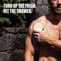Man washing with Silver Back soap in a stone outdoor shower